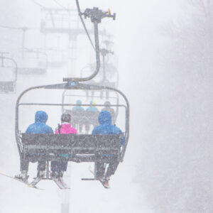 People riding the chairlift while snowing